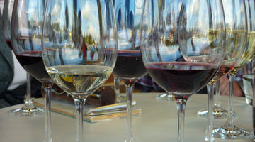 Viele Gläser Rotwein und Weißwein auf einem Tisch.