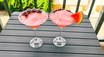 Auf dem Bild sind zwei Cocktail-Schalen zu sehen, die mit Frosé gefühlt sind. Einer ist mit Brombeeren garniert, der andere mit einer viertel Scheibe einer Wassermelone.