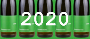 Auf dem Bild sind im Hintergrund fünf Flaschen Vinosaurier grün zu sehen. Sie sind unscharf. Im Vordergrund steht die Zahl 2020.