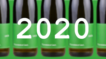 Auf dem Bild sind im Hintergrund fünf Flaschen Vinosaurier grün zu sehen. Sie sind unscharf. Im Vordergrund steht die Zahl 2020.