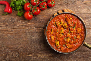 Indisches Vindaloo Curry in der Pfanne auf einem Tisch.