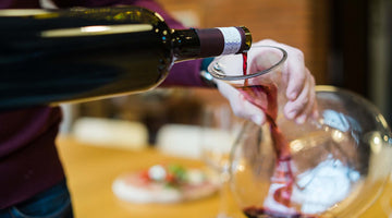 Person gießt Rotwein in einen Dekanter.