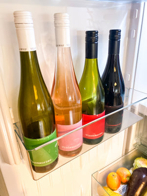 Das Bild zeigt die Innenseite einer Kühlschranktür. in der unteren Halterung stehen vier Flaschen Wein nebeneinander. V. r. n. l.: Vinosaurier grün, rosé, rot und schwarz. 
