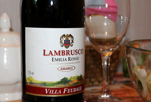 Eine Flasche Lambrusco, daneben ein leeres Weinglas.