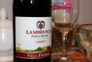Eine Flasche Lambrusco, daneben ein leeres Weinglas.