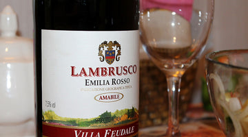 Eine Flasche Lambrusco, daneben ein leeres Weinglas.