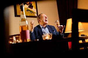 Stefan Maas trinkt ein Glas Wein gestikuliert wild und lacht.