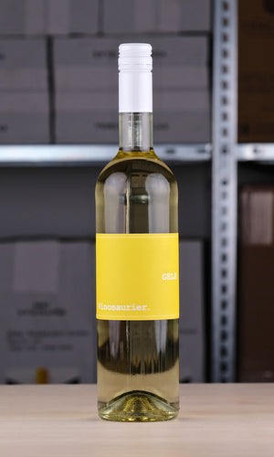 Eine Flasche Vinosaurier Gelb vor einem Regal fotografiert. Die Flasche ist aus weißem Glas, sodass direkt der Weißwein zu erkennen ist. Der Verschluss ist ebenfalls weiß. Das Etikett ist gelb mit weißer Schrift.