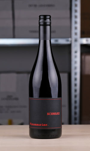 Der Rotwein Vinosaurier Schwarz in einem Lager vor einem Regal.