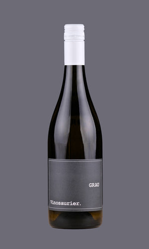 Eine Flasche Vinosaurier Grau vor einem grauen Hintergrund. Die Flasche ist aus braunem Glas. Der Verschluss ist weiß. Das Etikett ist grau mit weißer Schrift.