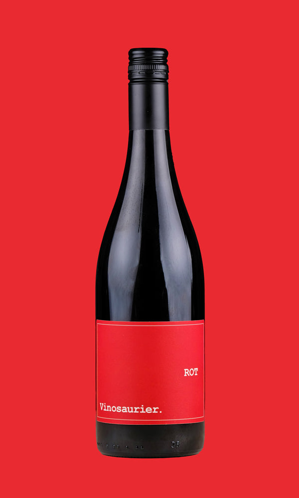 Eine Flasche Vinosaurier rot vor einem roten Hintergrund. Die Färbung der Flasche ist aufgrund der dunklen Farbe des Rotweins nicht zu kennen. Der Verschluss ist schwarz das Etikett ist rot mit weißer Schrift. 