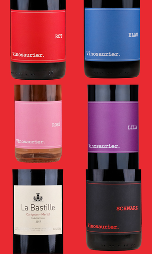 Eine Grafik mit rotem Hintergrund. Darauf die Etiketten von sechs Weinflaschen. Drei rechts und drei links. Links im Bild: Vinosaurier Rot, Rosé und La Bastille Rouge. Rechts im Bild: Vinosaurier Blau, Lila und Schwarz. 